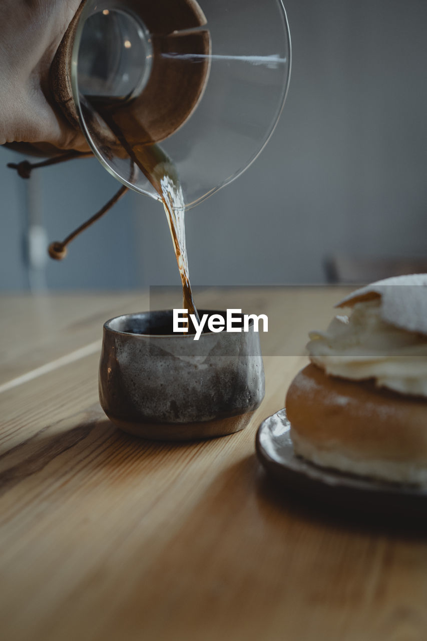 Traditional semla bun on plate and pouring coffee