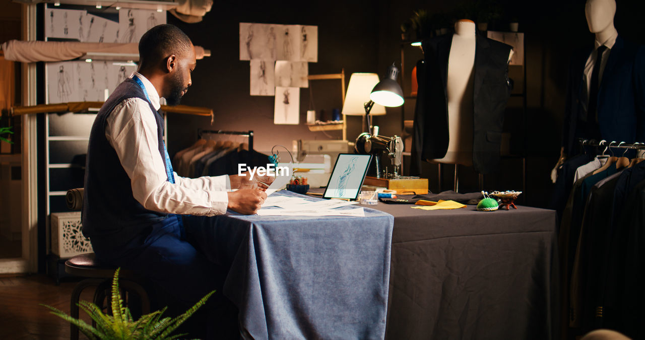 rear view of woman using digital tablet while sitting on table