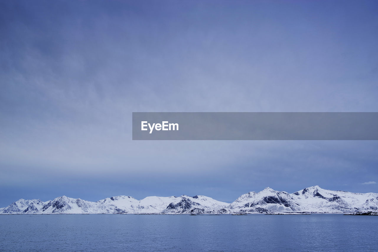 Scenic view of snowcapped mountains by sea against sky