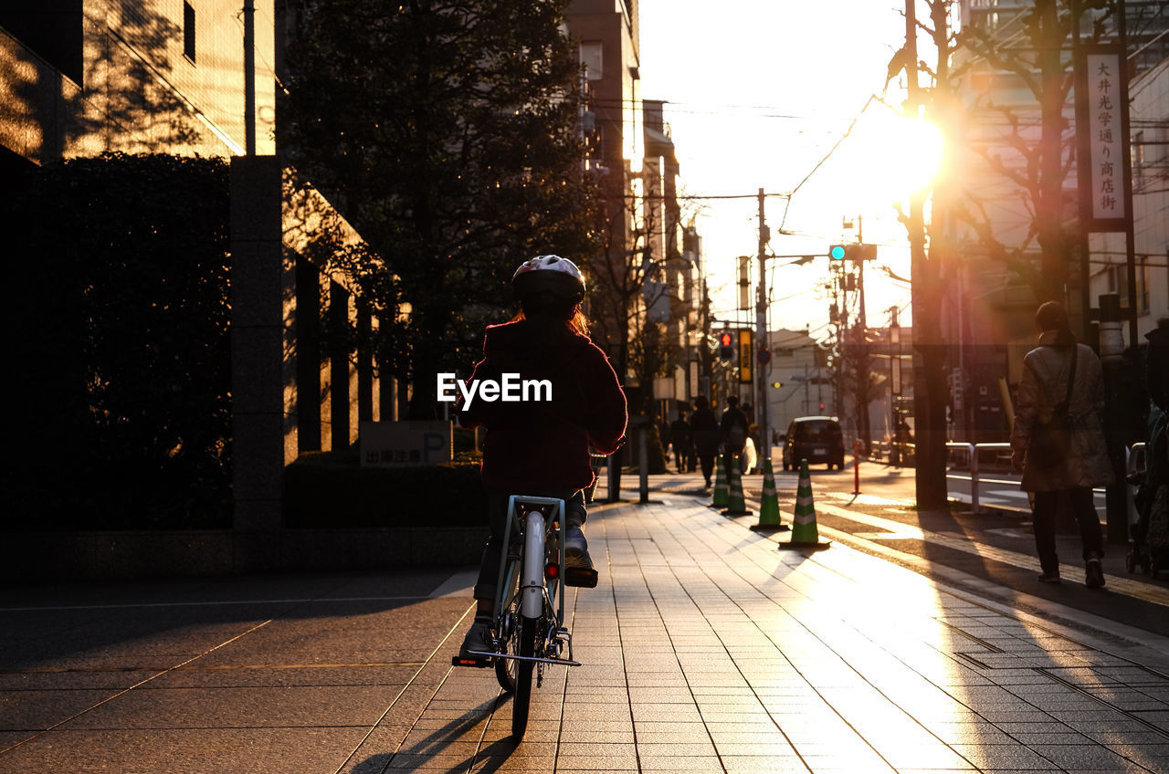 Rear view of girl riding bicycle on footpath in city