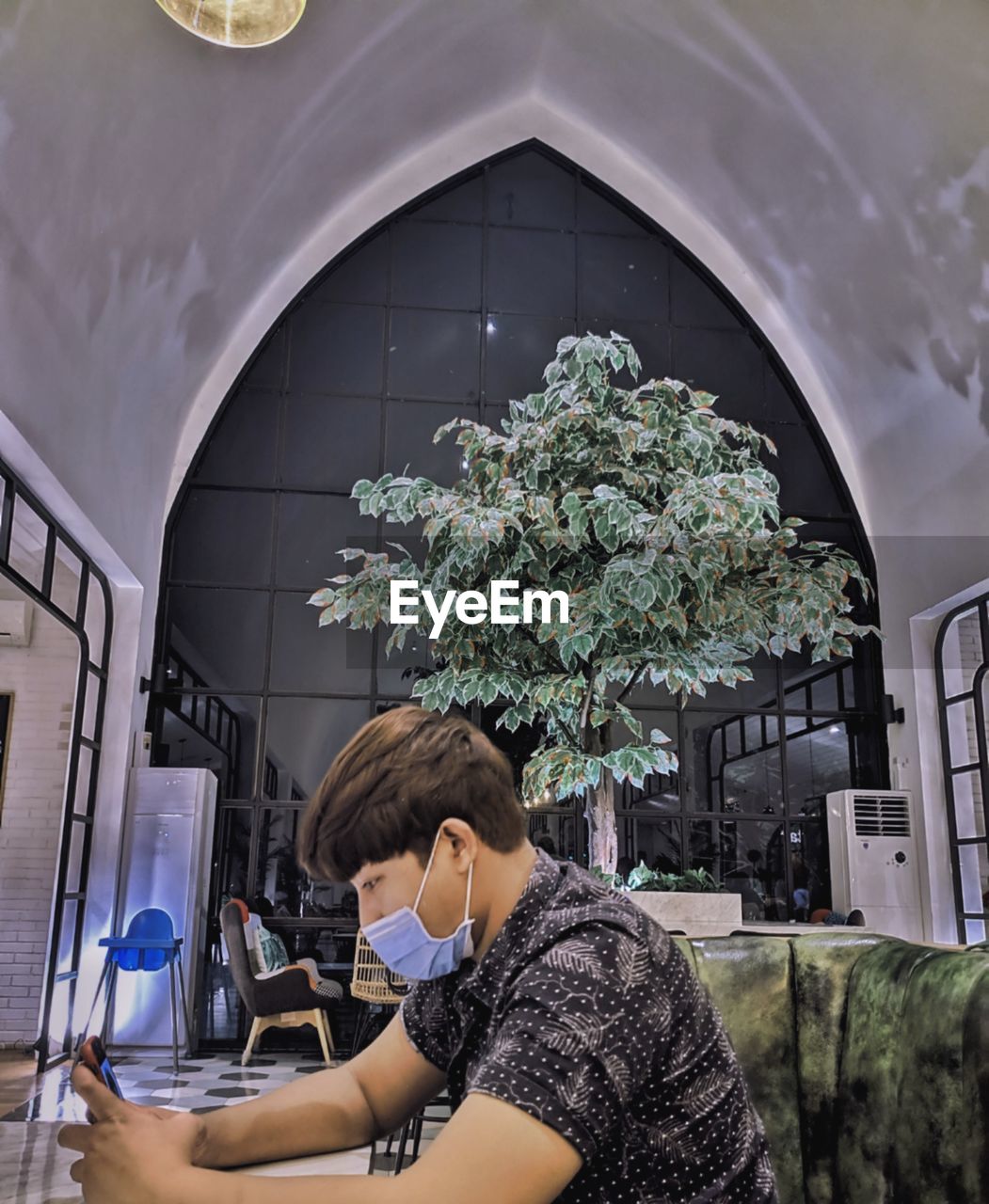 Young man wearing mask sitting in building