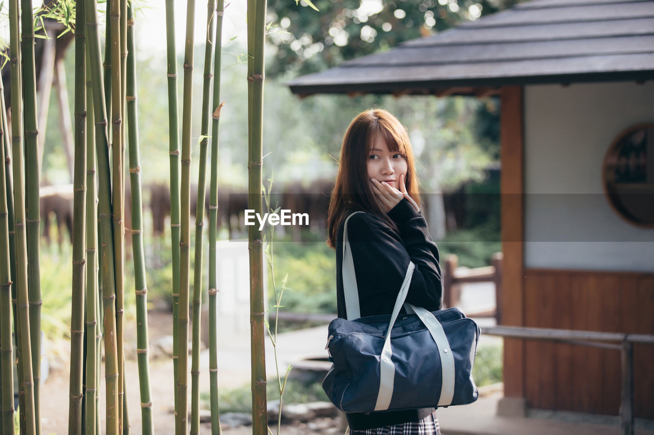 PORTRAIT OF YOUNG WOMAN STANDING OUTDOORS