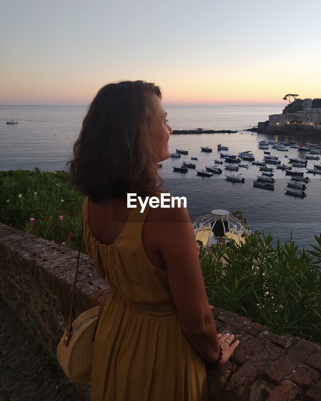 Rear view of woman looking at sea against sky during sunset