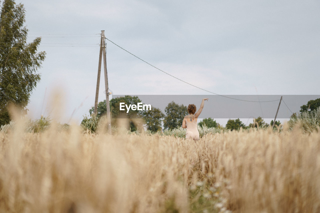 Woman standing on field against sky