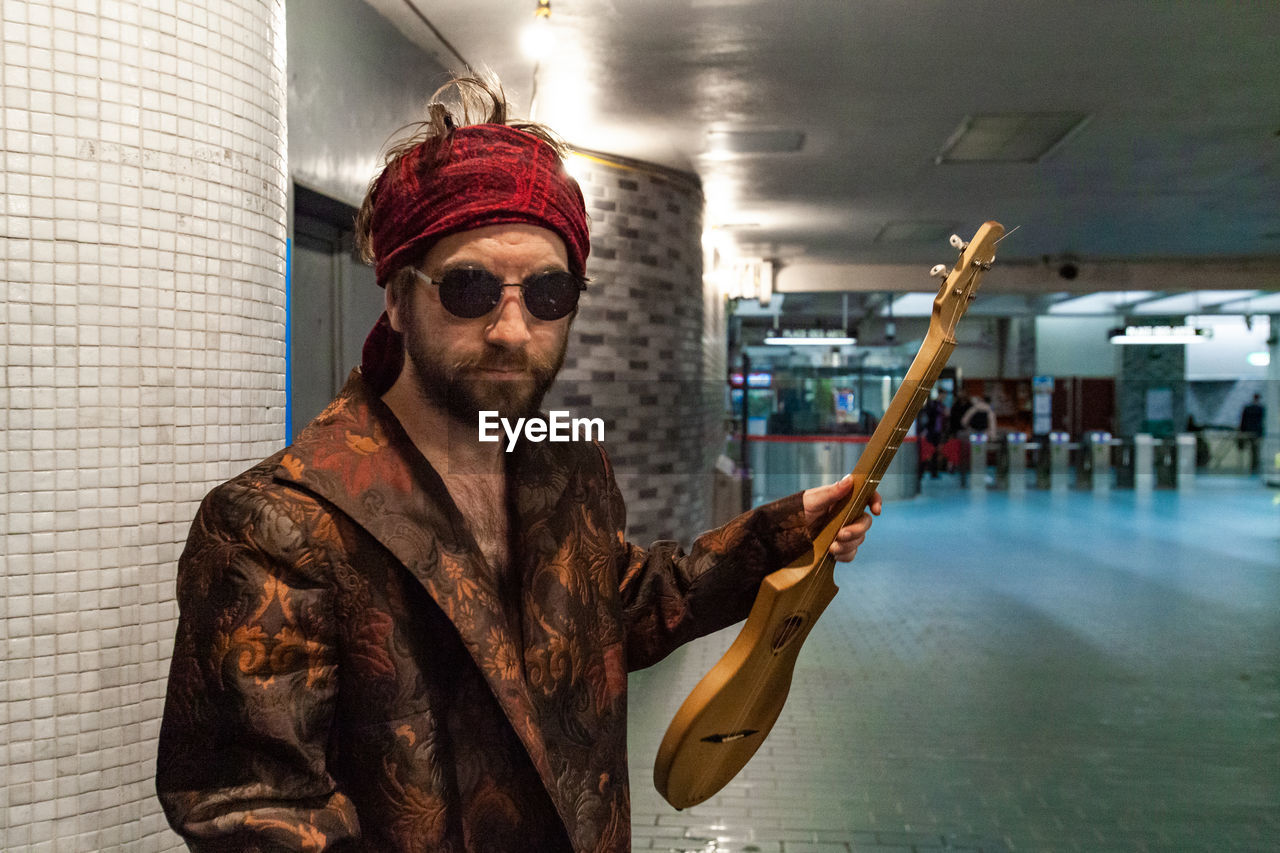 MAN WEARING SUNGLASSES STANDING AGAINST WALL