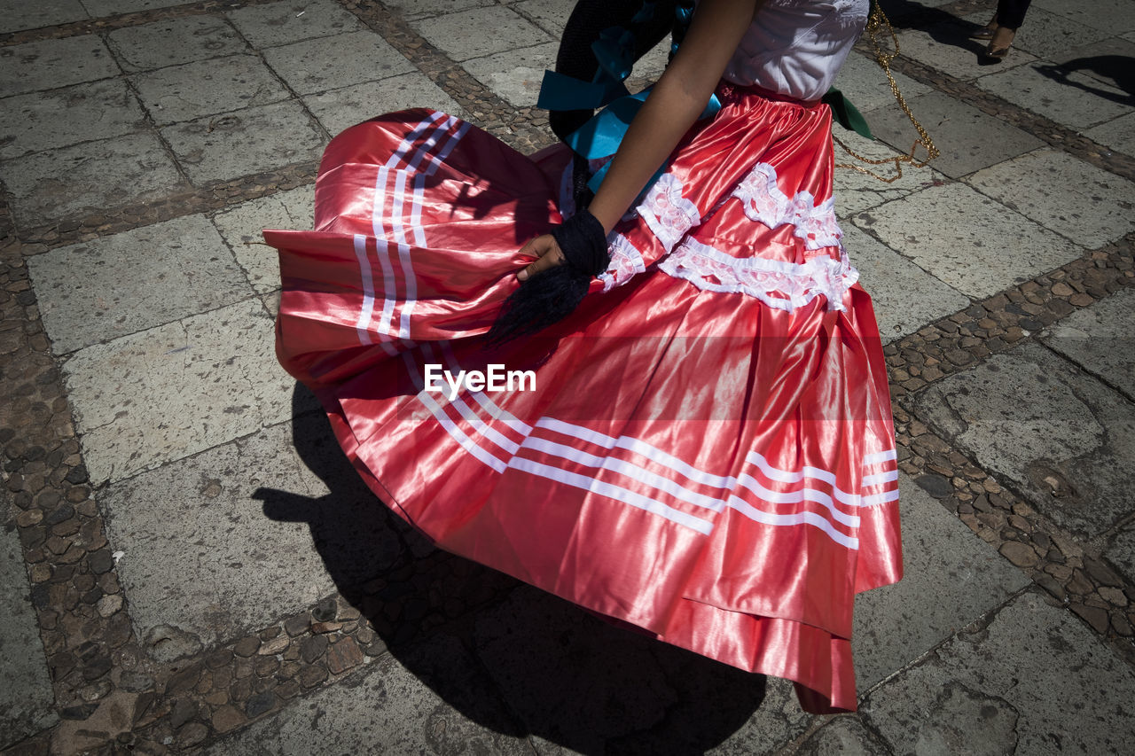 Low section of woman in red skirt walking on footpath