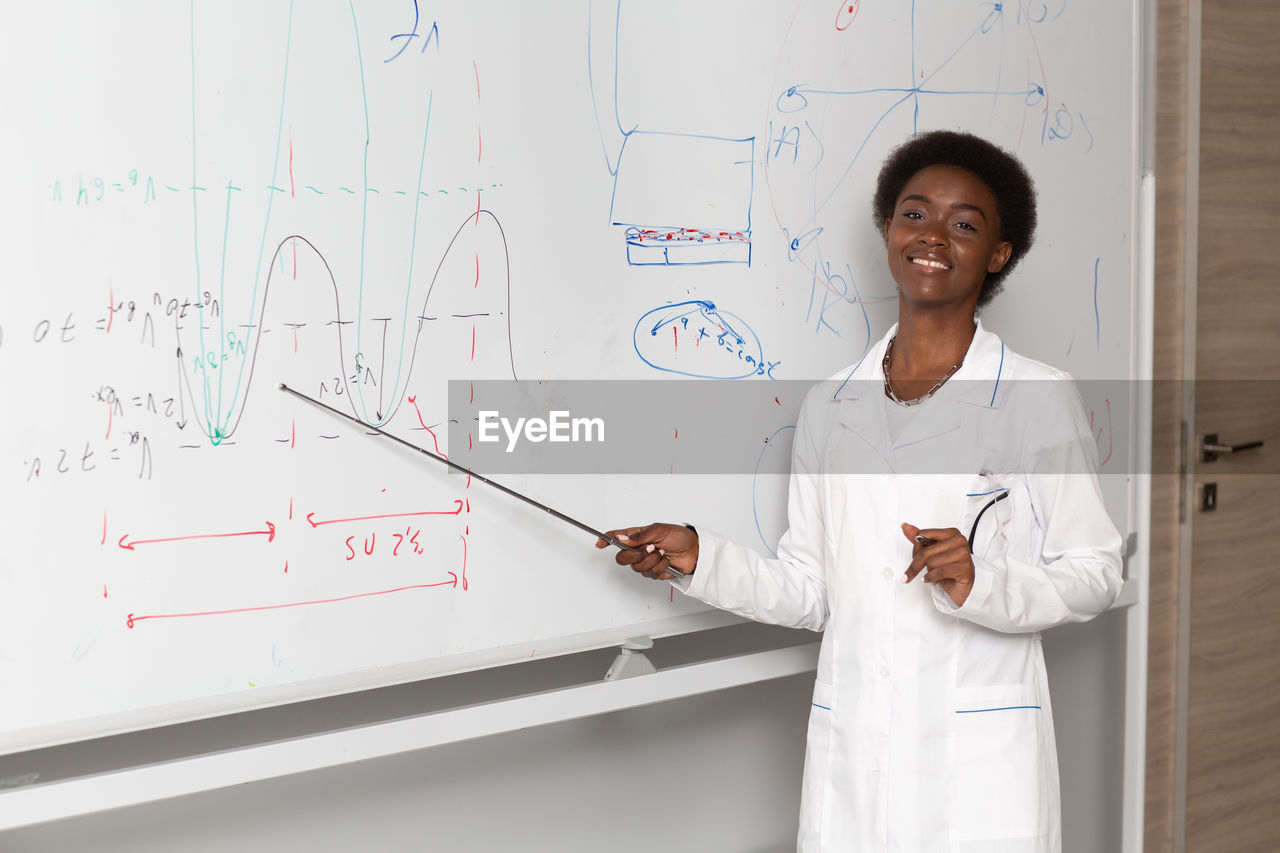 portrait of female doctor standing against white wall