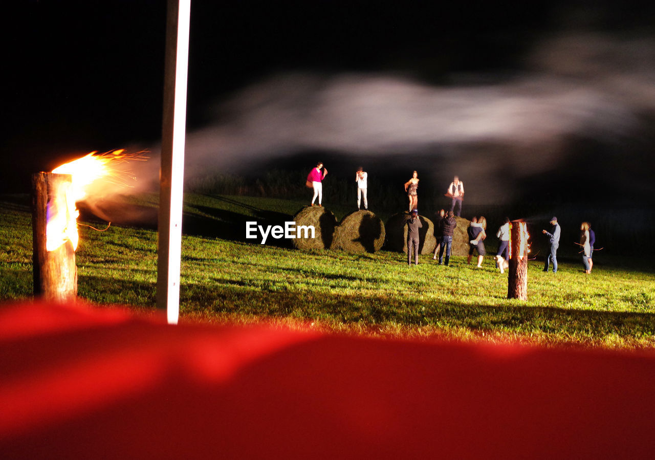 PEOPLE AT FIELD AGAINST SKY AT NIGHT