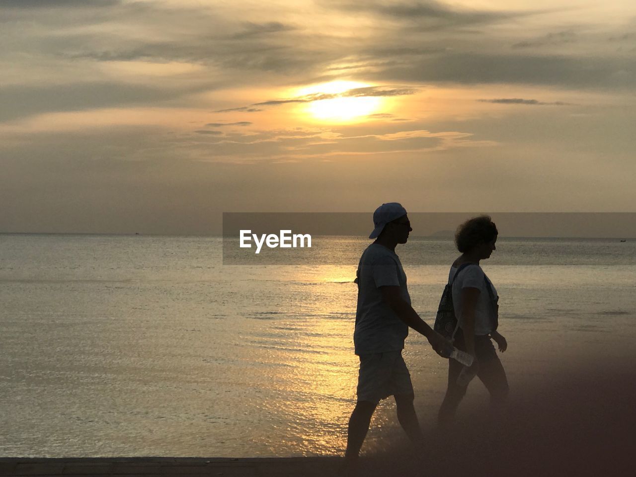 FRIENDS ON BEACH AGAINST SKY AT SUNSET