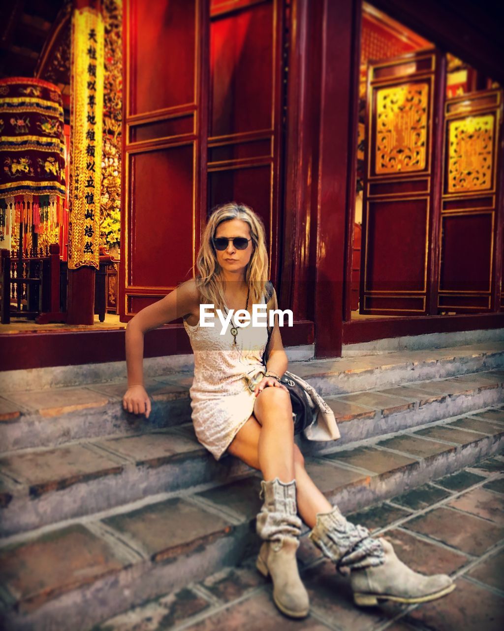 Full length portrait of woman sitting on steps at religious building