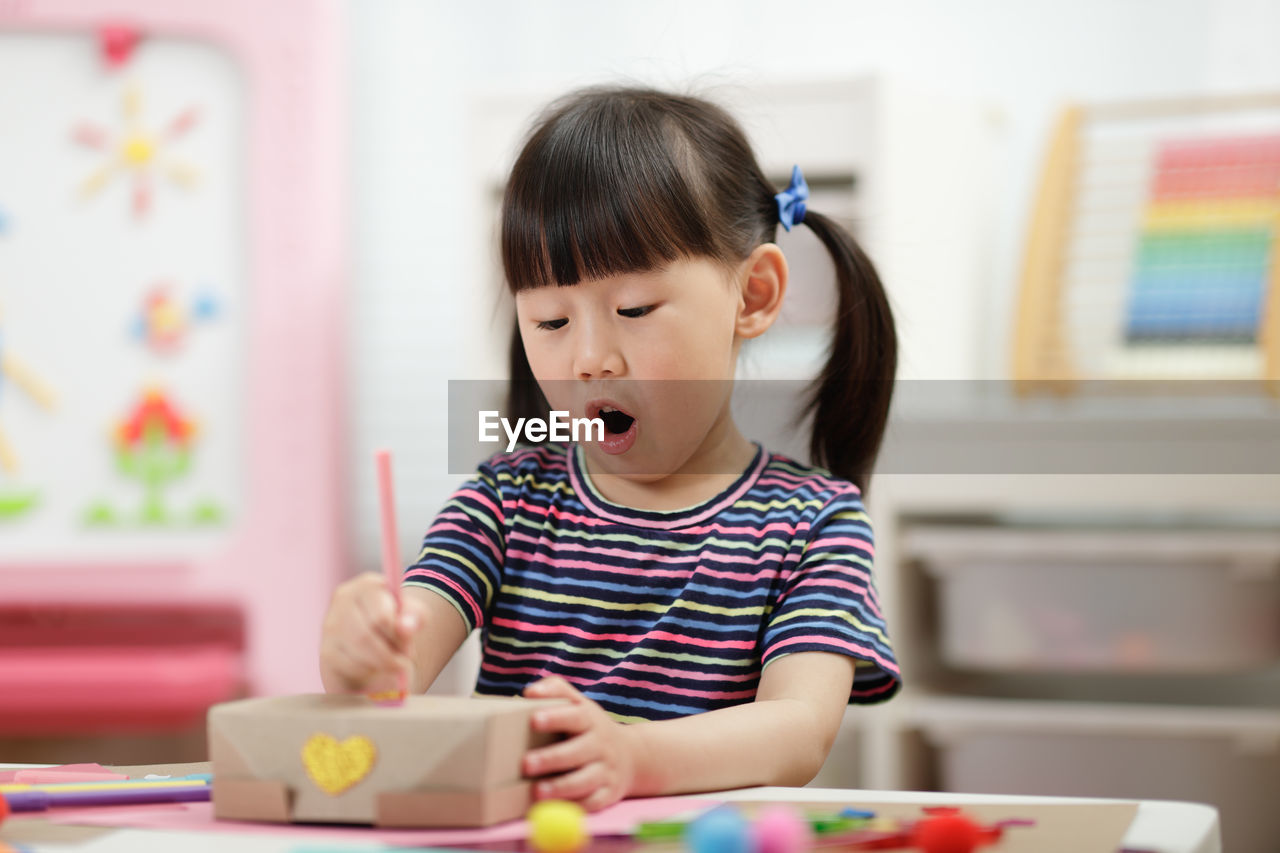 Young girl decorating hand made craft for homeschooling