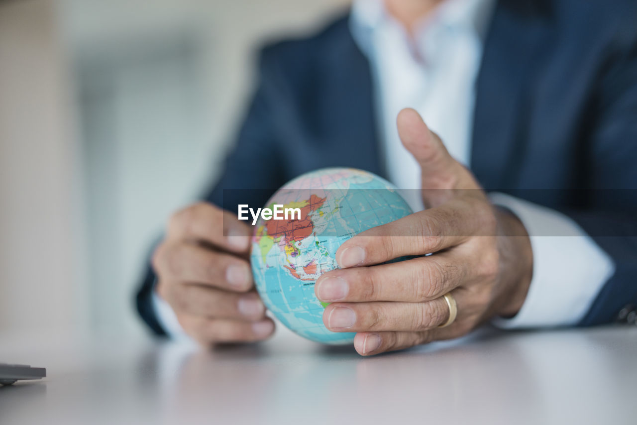 Close-up of hands of businessman holding globe