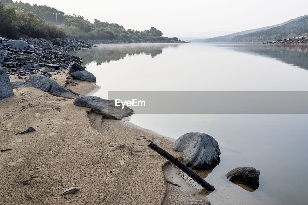 SCENIC VIEW OF ROCKS IN LAKE AGAINST SKY