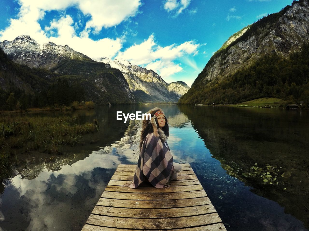 Woman sitting by lake on jetty