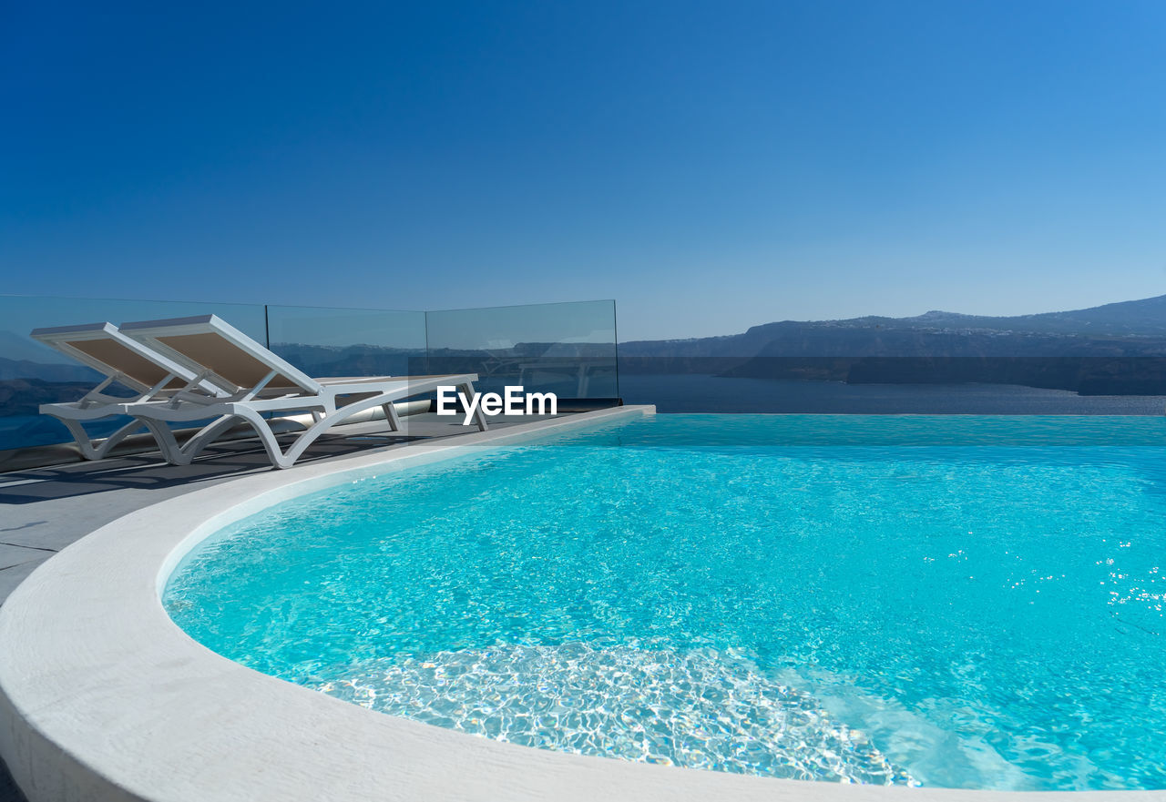 Lounge chair and pool over santorini caldera. akrotiri, santorini island, cyclades, greece, europe.