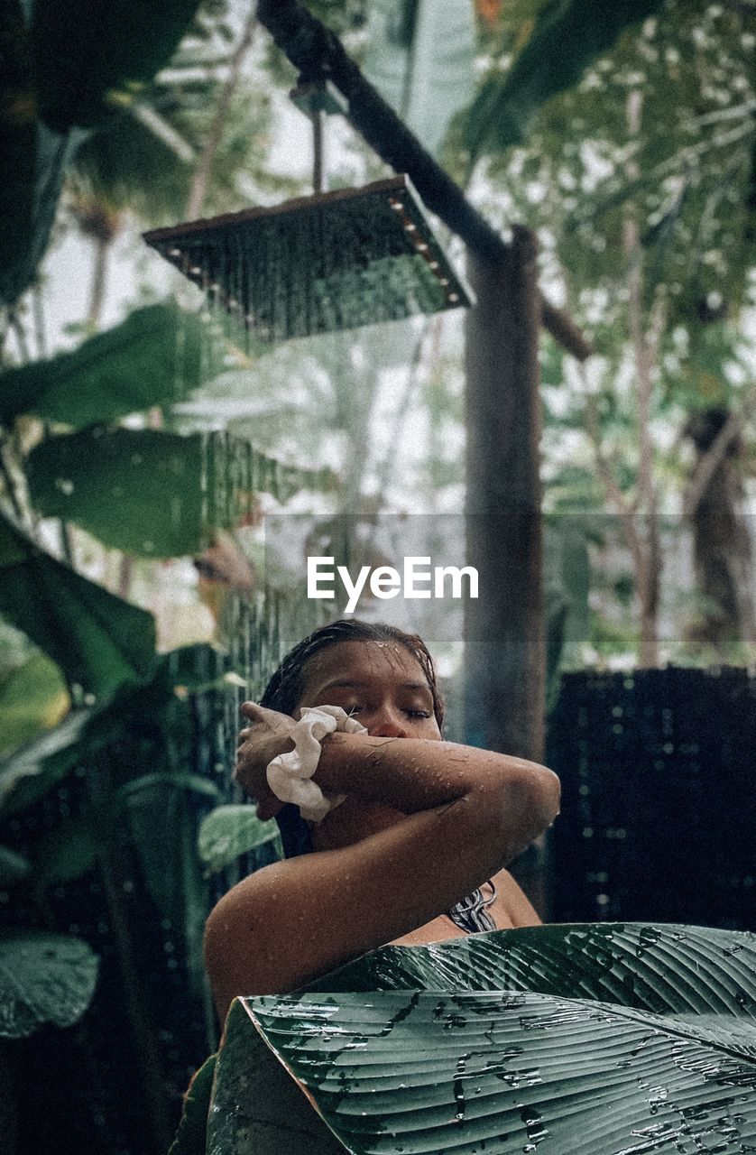 Woman taking shower amidst plants