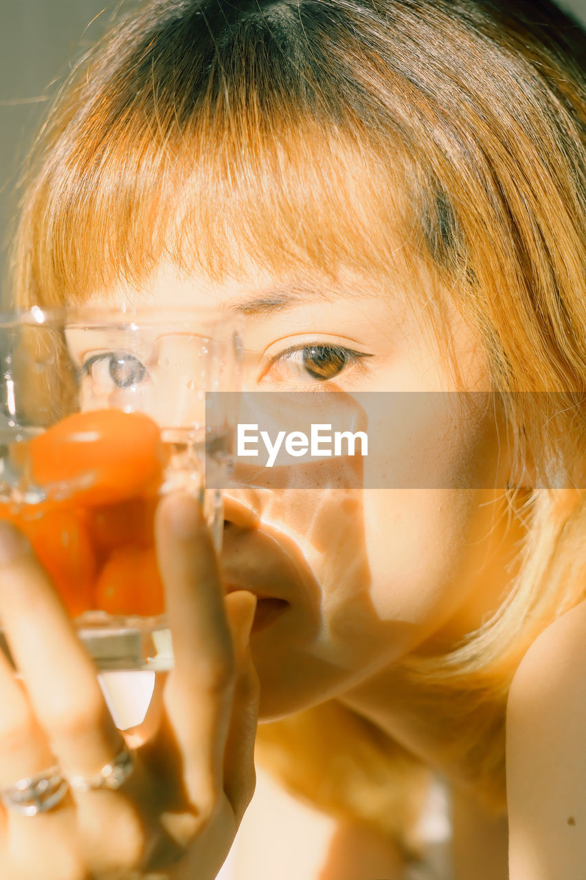 Close-up portrait of woman holding drinking glass