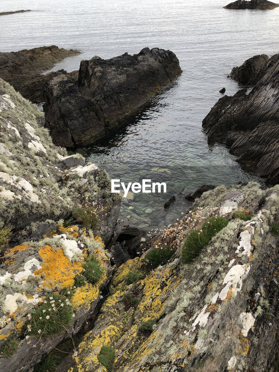 HIGH ANGLE VIEW OF ROCK FORMATIONS ON SEA