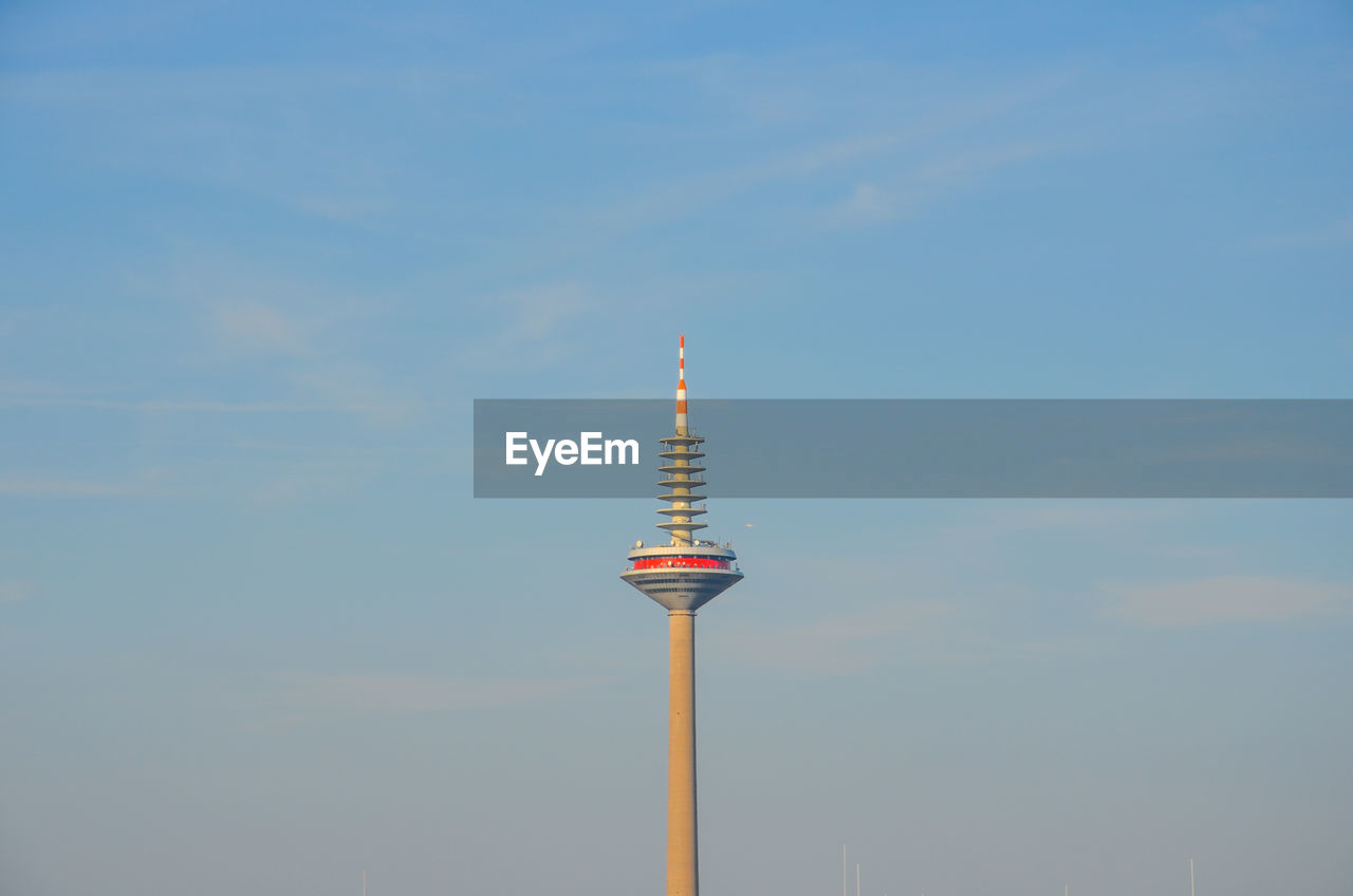 Low angle view of communications tower in sunlight against sky