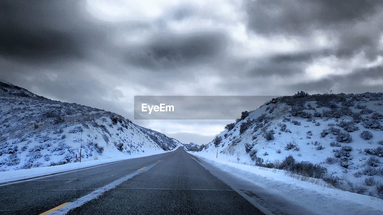 Road amidst snowcapped mountains against sky