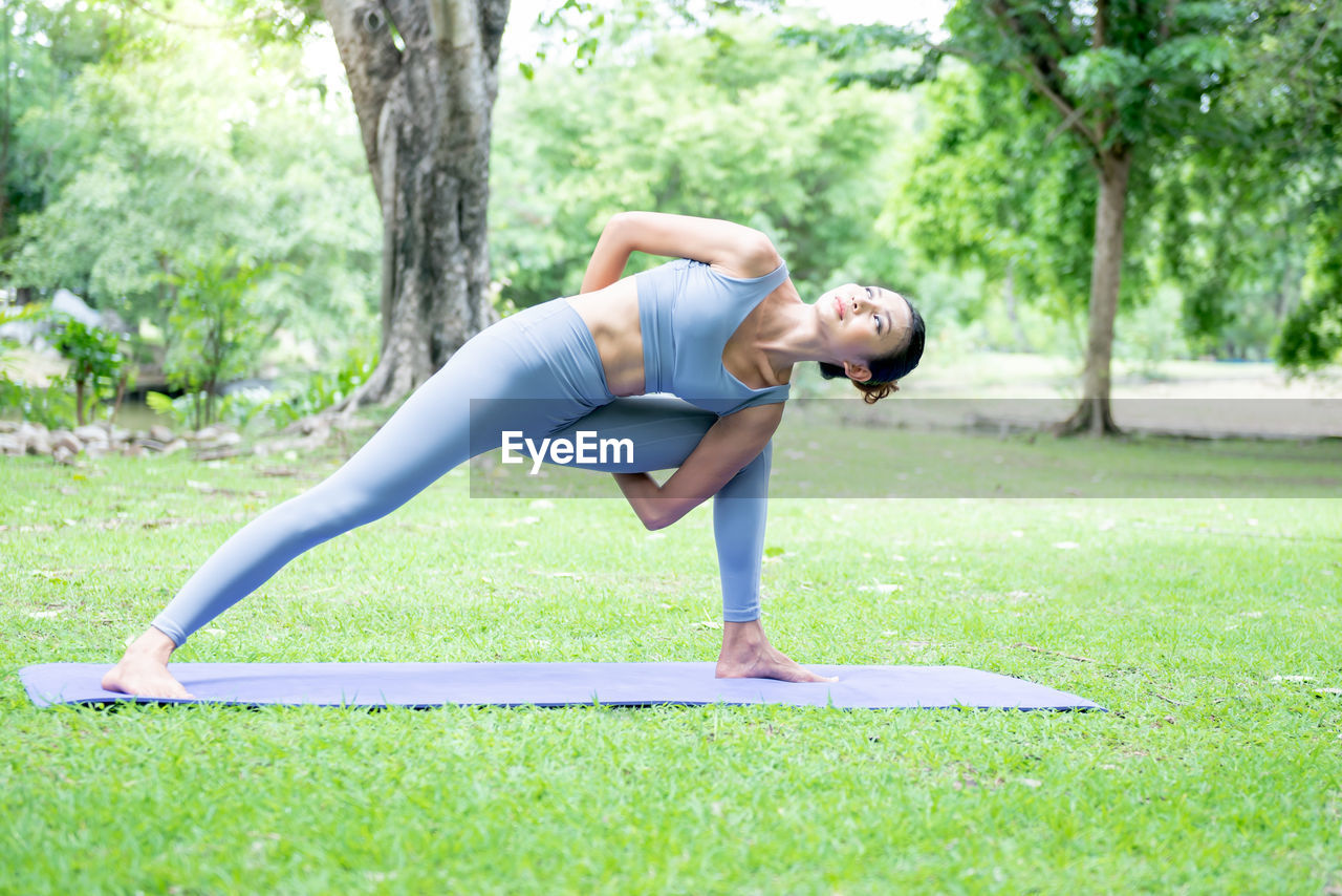 FULL LENGTH OF WOMAN WITH ARMS OUTSTRETCHED ON GRASS