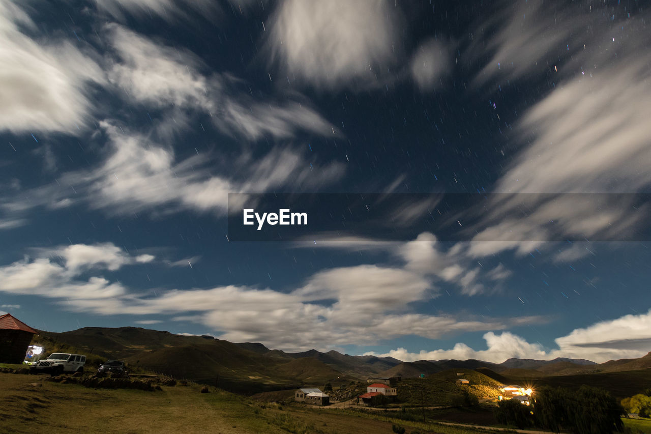 Scenic view of houses by mountains against sky