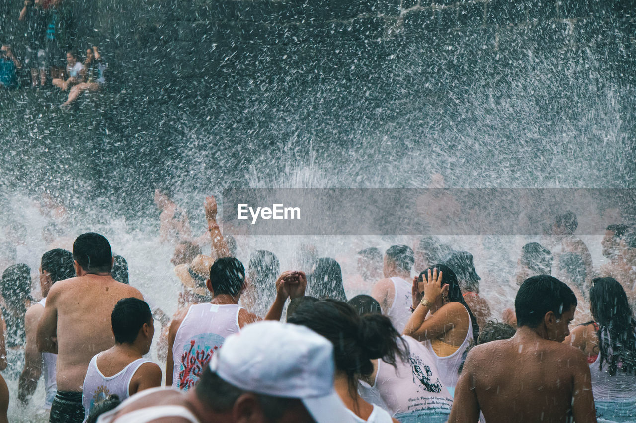 REAR VIEW OF PEOPLE AT SEA SHORE