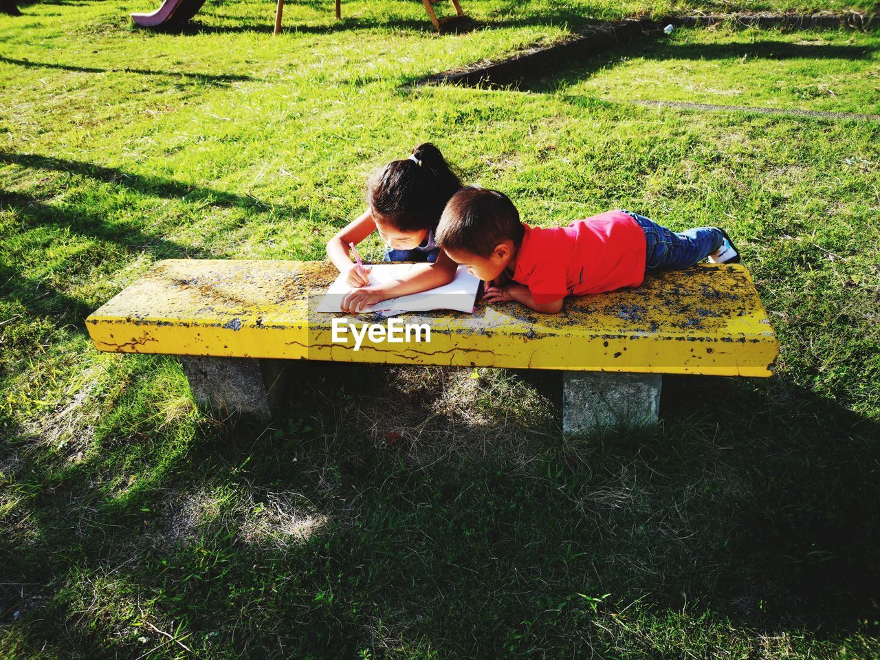 High angle view of siblings doing homework on table in park