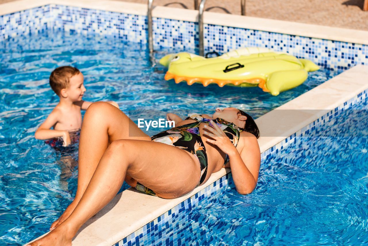 Young woman lying on railing in swimming pool