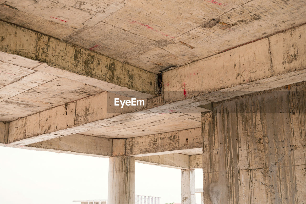 Looking up to see the size of concrete beams against old and dilapidated concrete floors. beams.