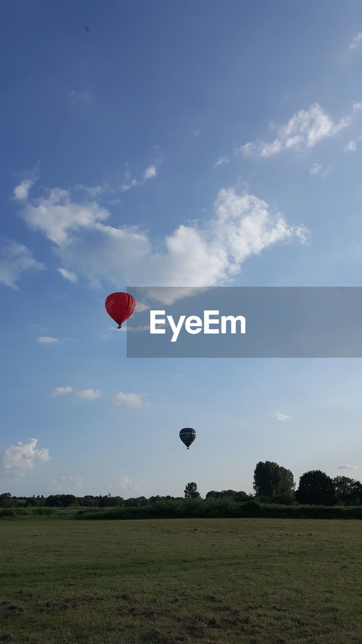 HOT AIR BALLOONS FLYING OVER FIELD