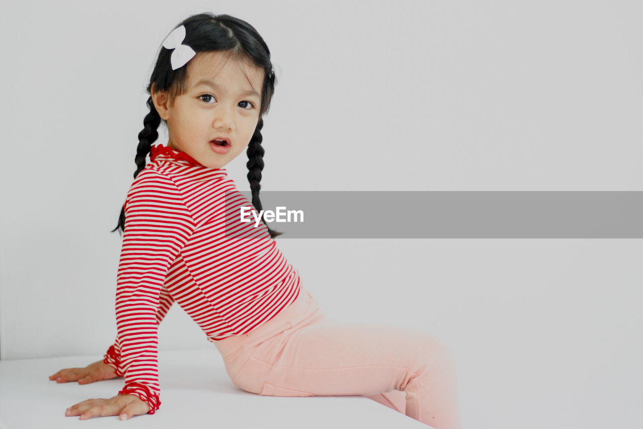 full length of young woman sitting on exercise mat against white background