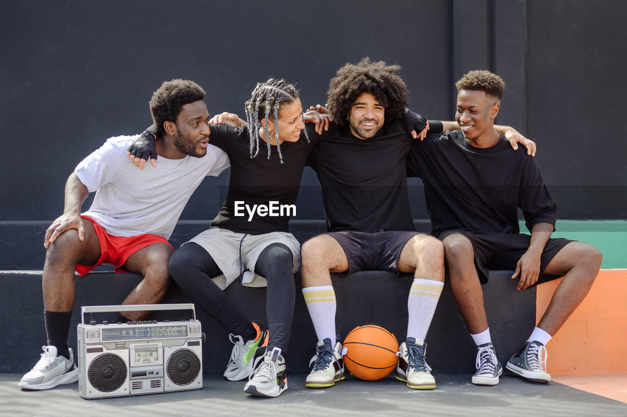 Multi-ethnic friends with basketball listening to music