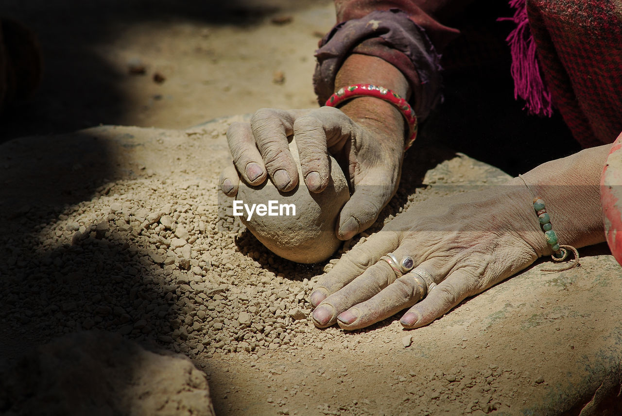 Cropped hands of woman holding rock on land