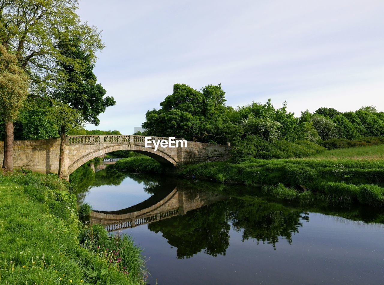 Arch bridge over river against sky