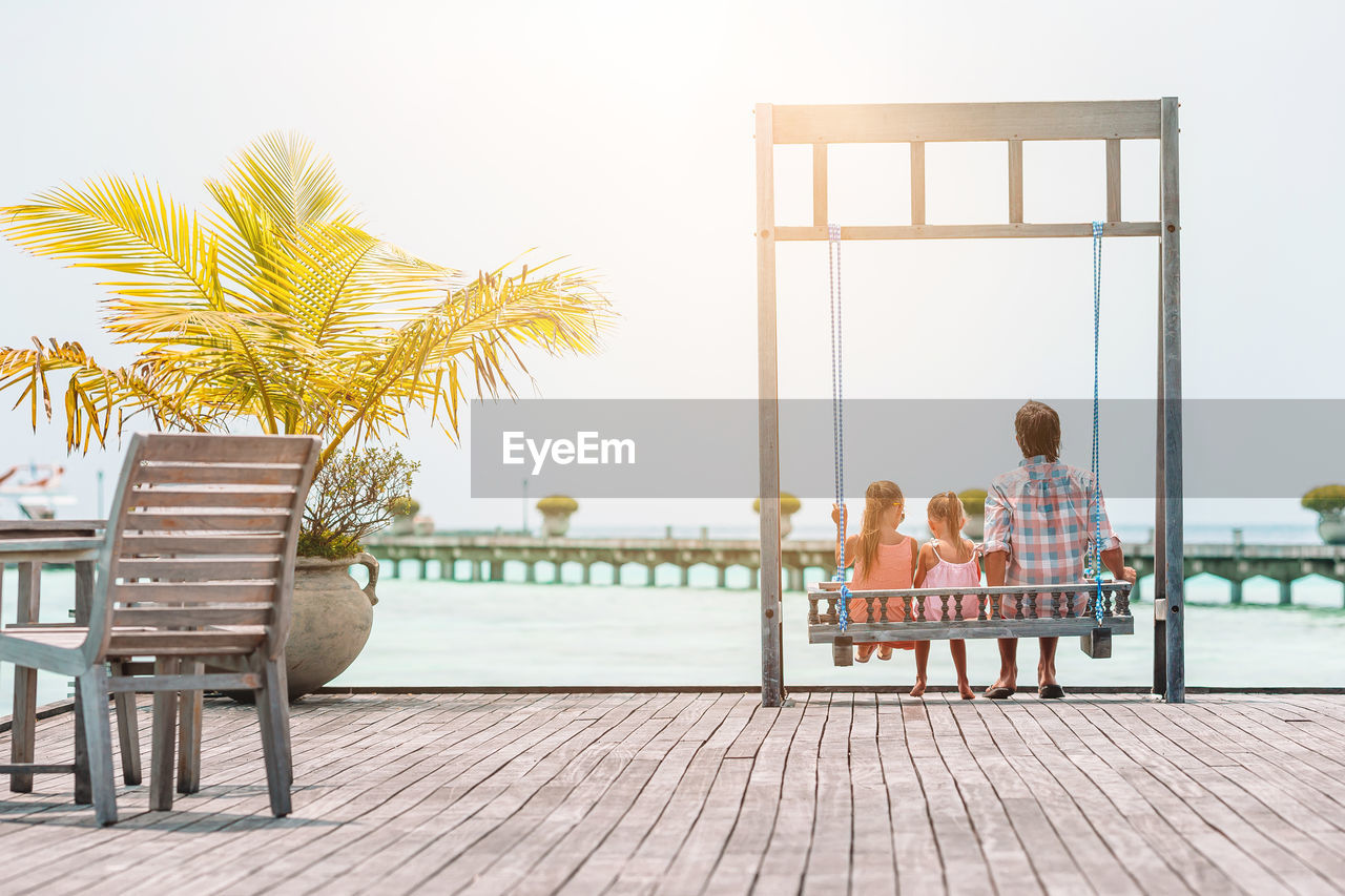 PEOPLE SITTING ON BENCH BY CHAIR