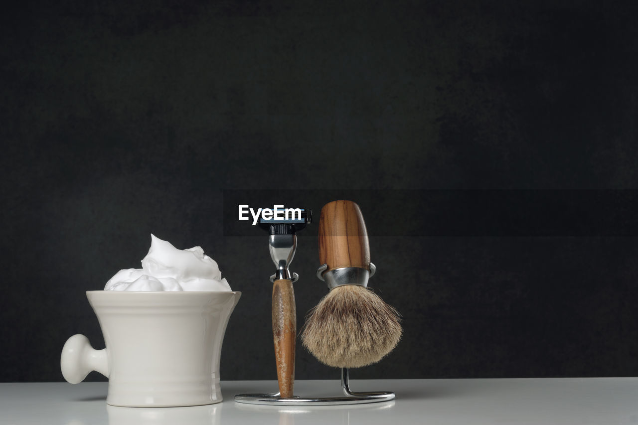 Close-up of shaving equipment on table against black background