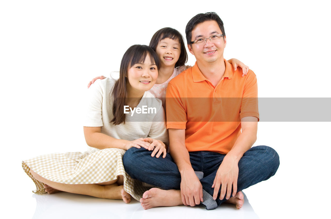 Smiling parents with daughter against white background