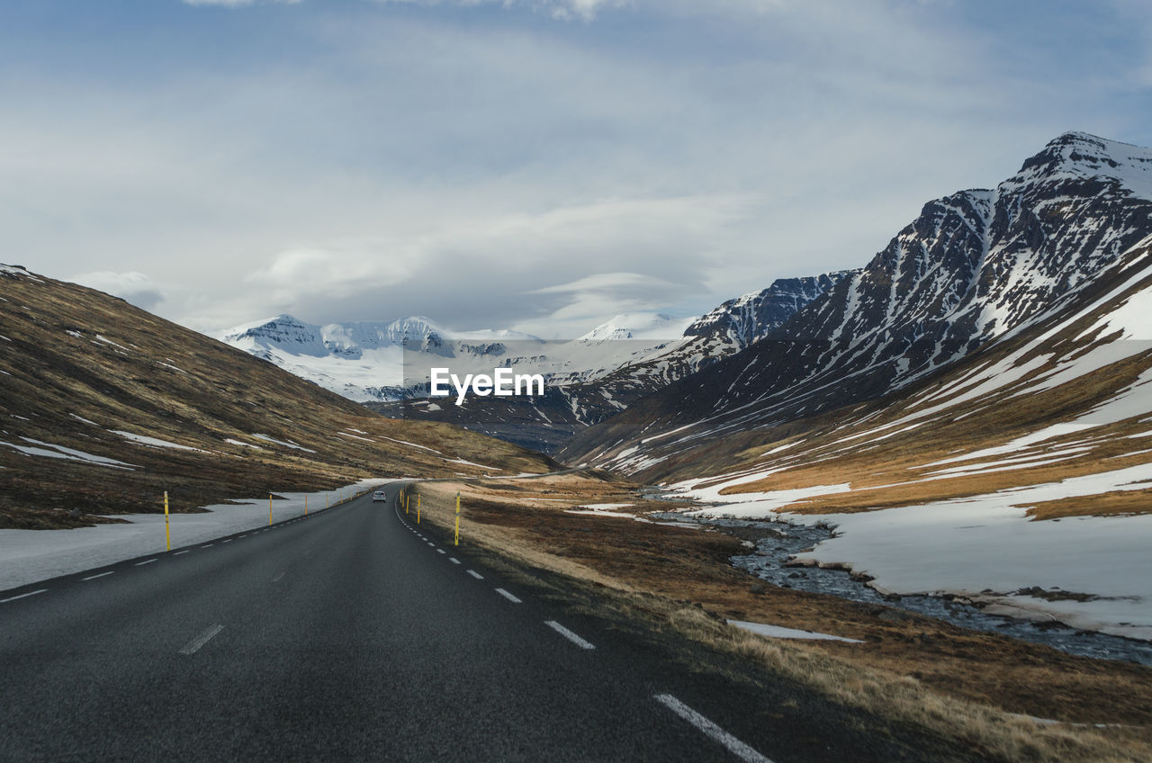 Road amidst snowcapped mountains against sky