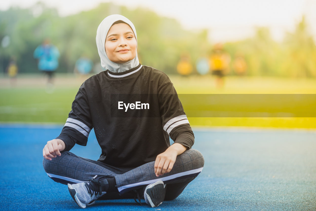 Thoughtful female athlete sitting at stadium