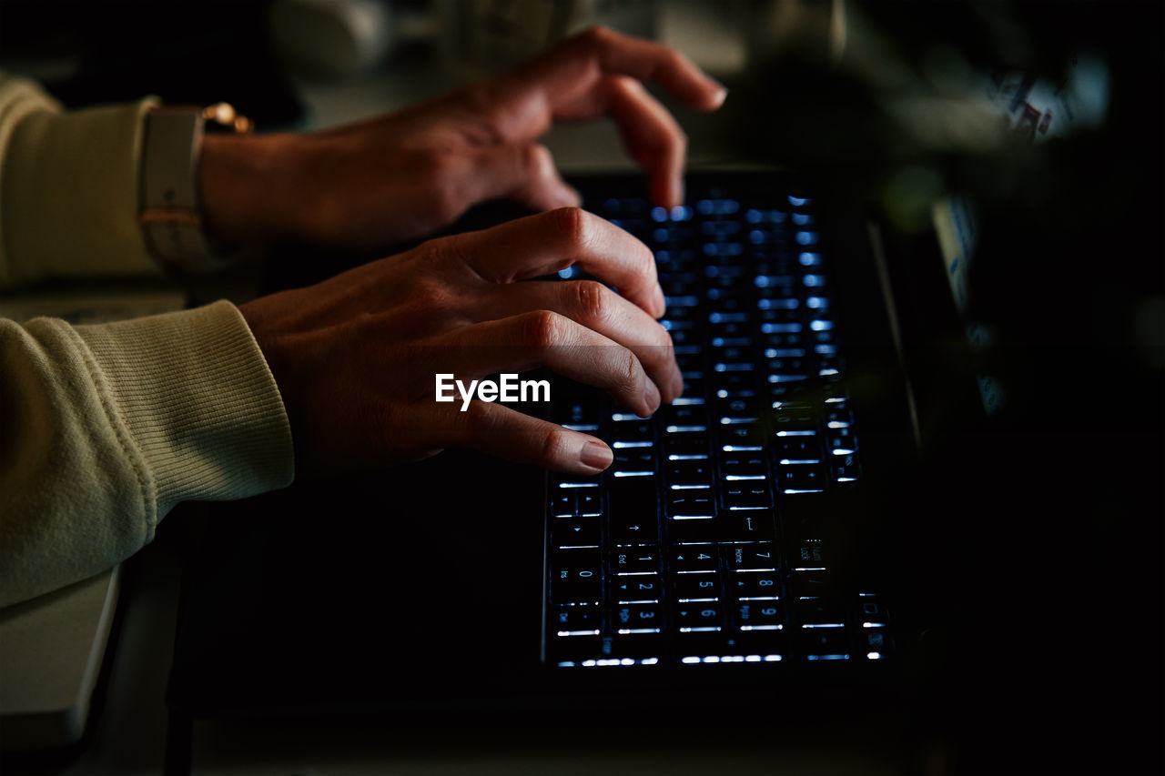 Anonymous woman working on laptop at night