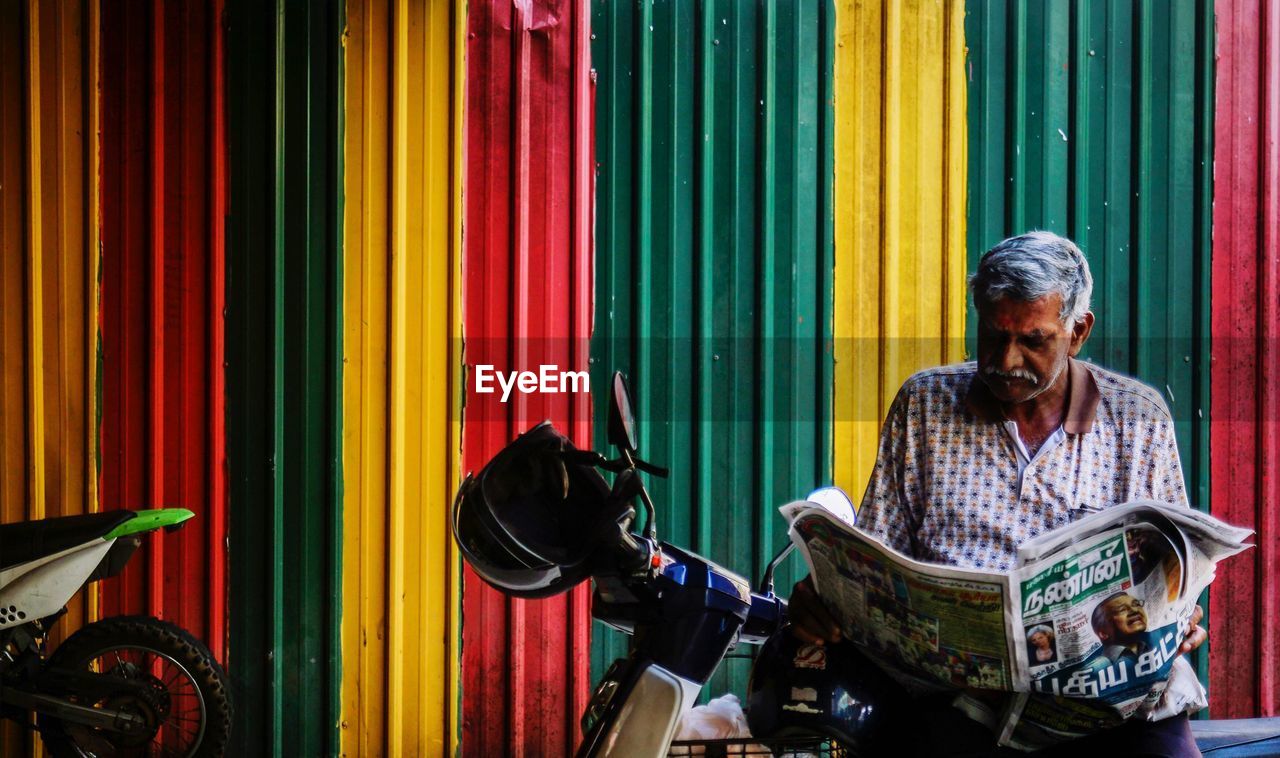 Senior man reading newspaper while sitting on motorcycle