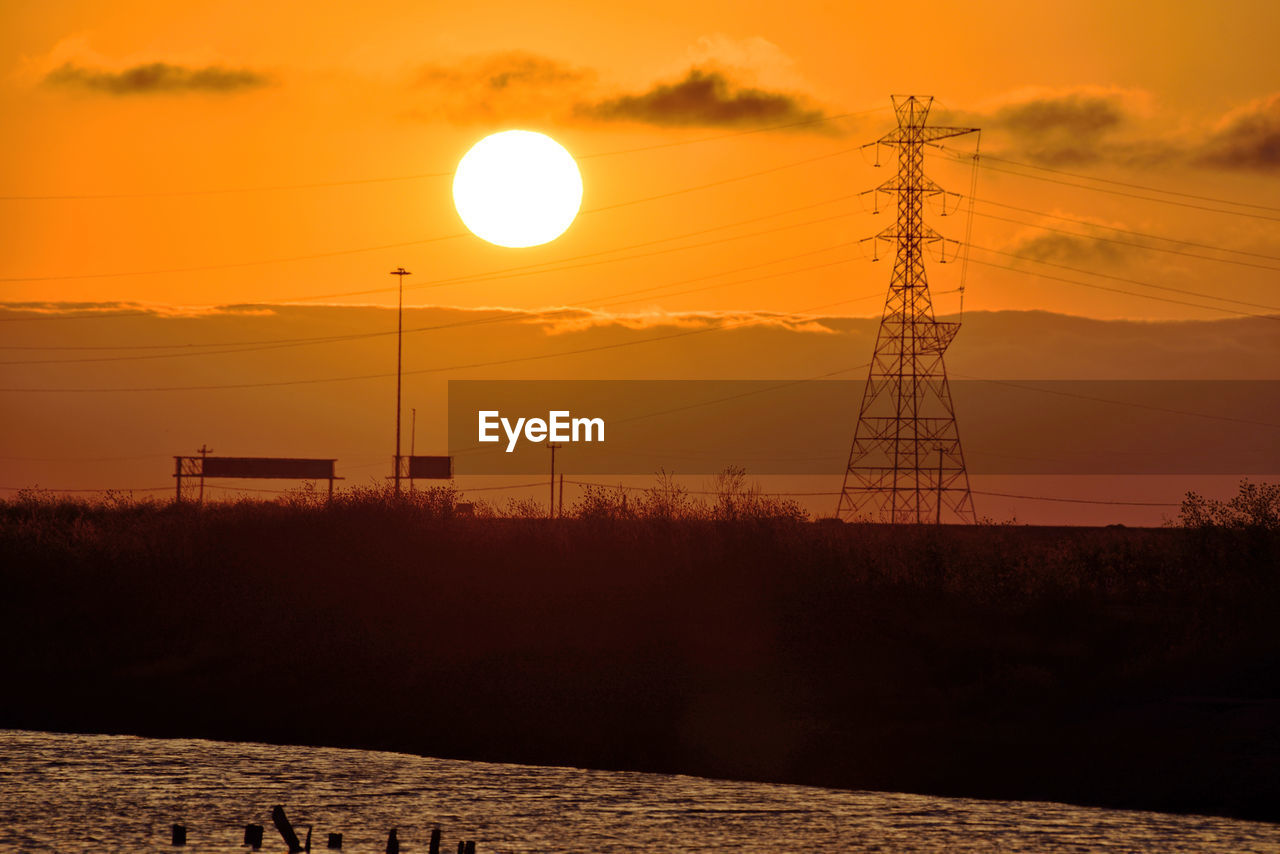 SILHOUETTE ELECTRICITY PYLONS AGAINST ORANGE SKY