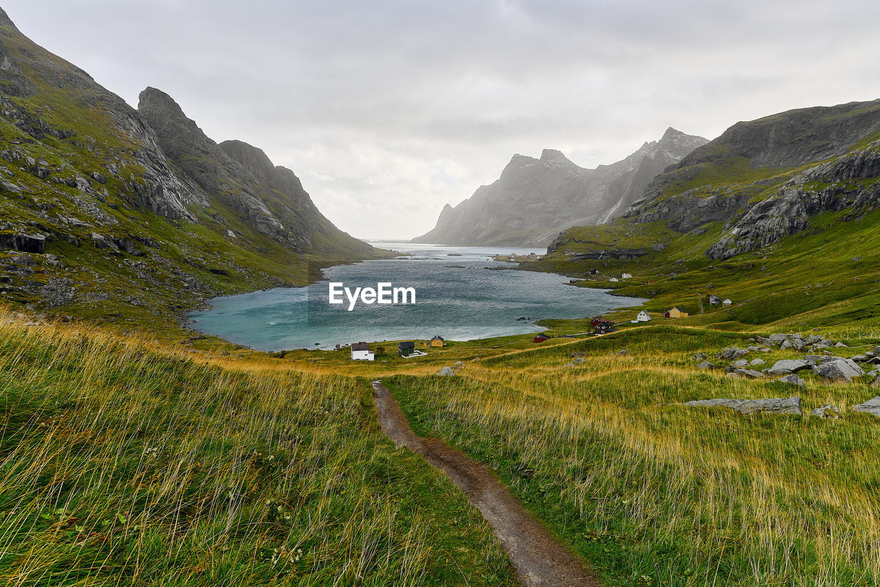 Scenic view of hiking trail leading to houses in village vinstad at the coast in lofoten norway