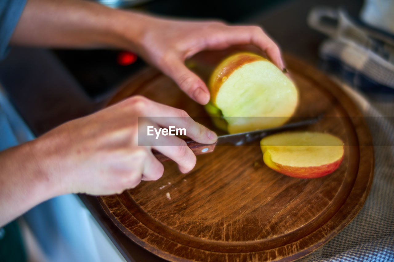 Cropped hands of woman cutting apple at home