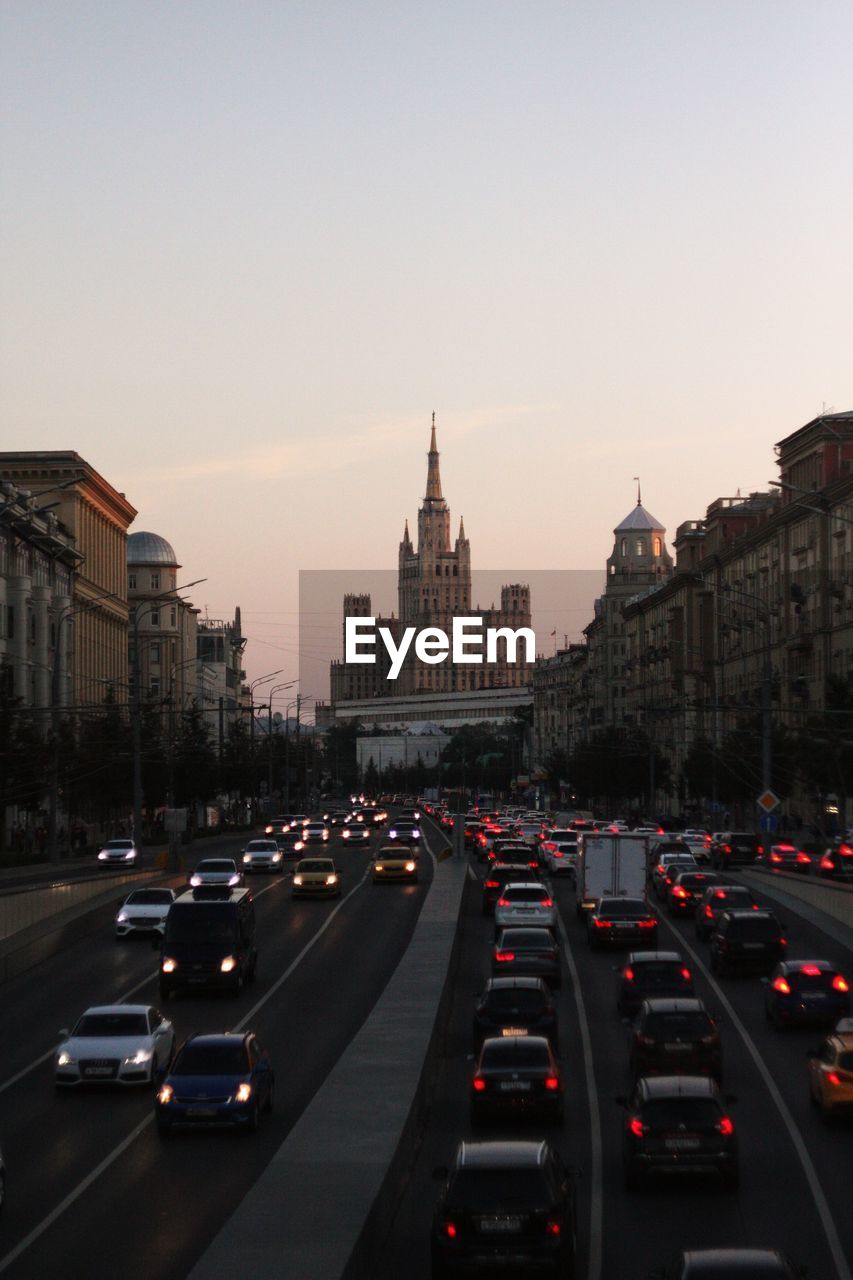 TRAFFIC ON CITY STREET AGAINST SKY DURING SUNSET