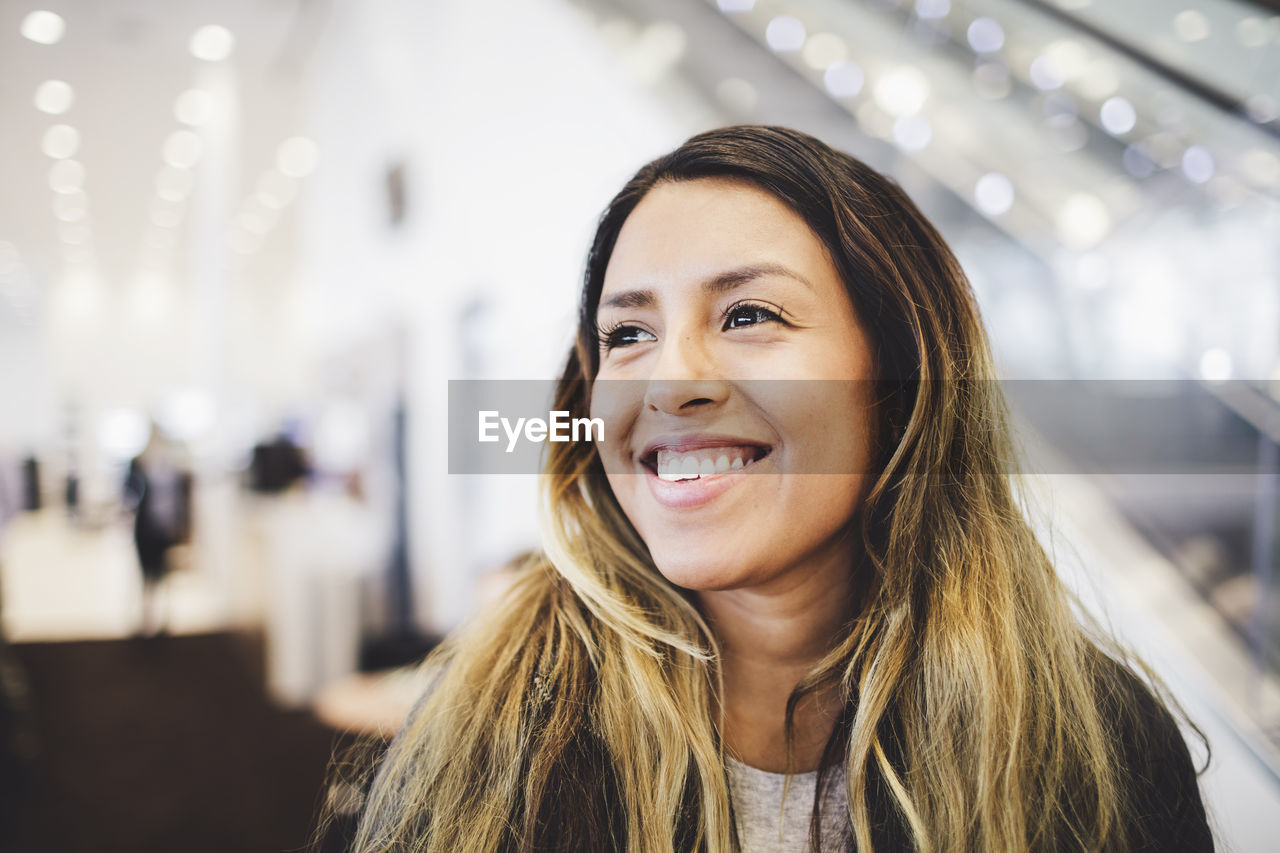 Smiling young woman standing at car showroom