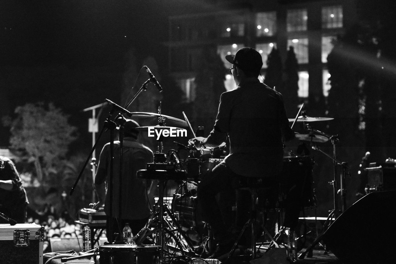 Rear view of musicians playing musical equipment during concert