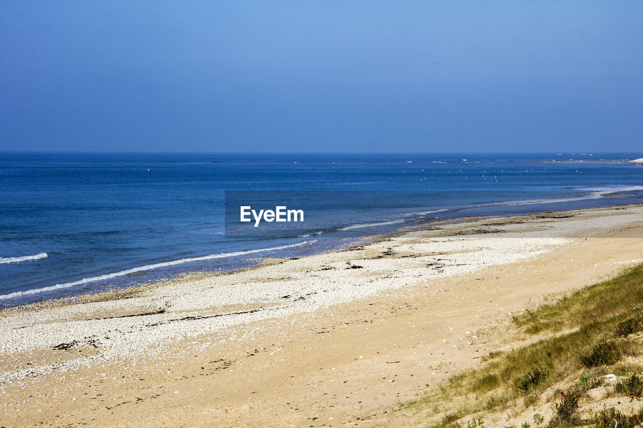 Scenic view of beach against clear blue sky