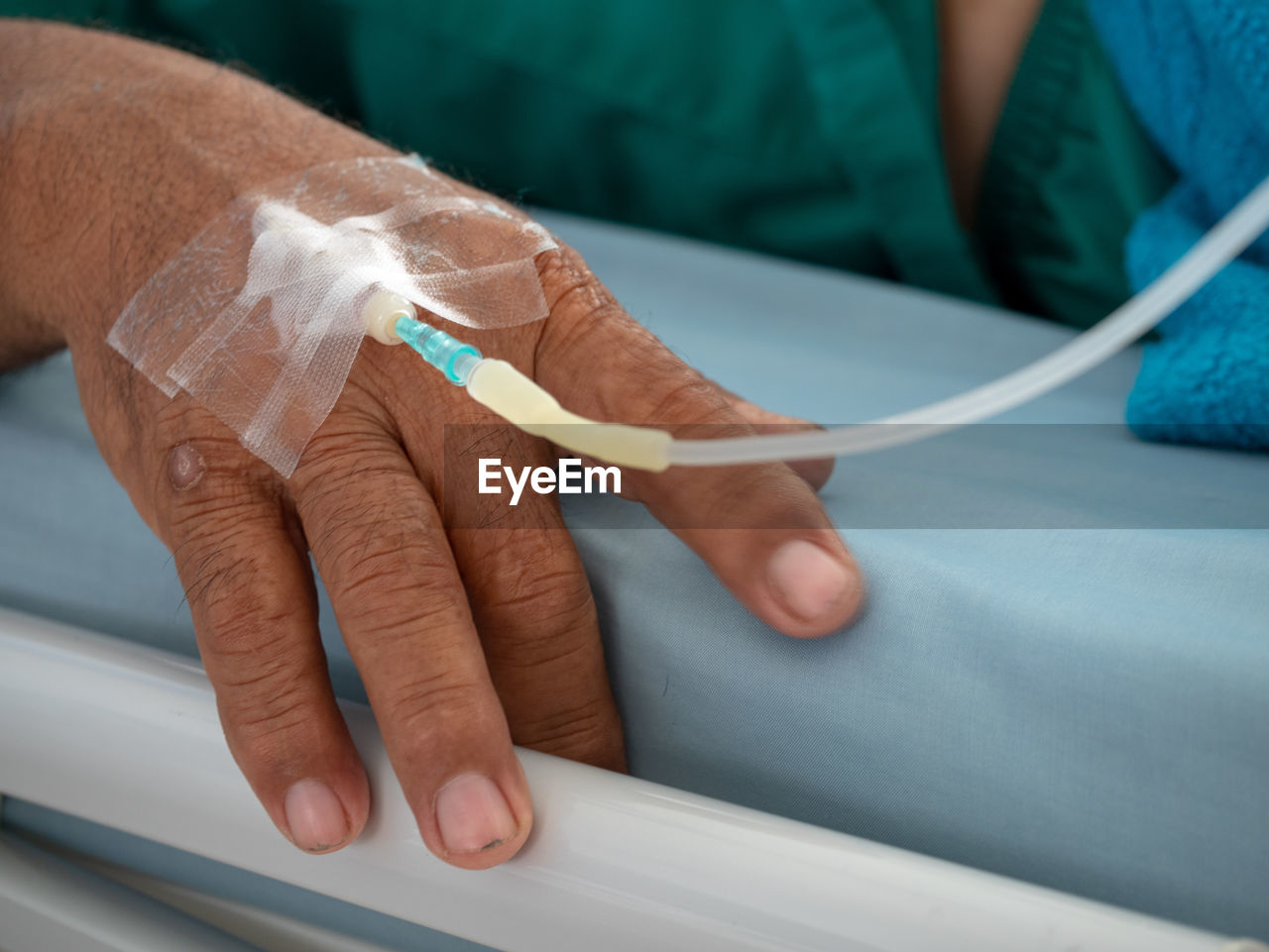 Close-up of human hand with iv drip on bed